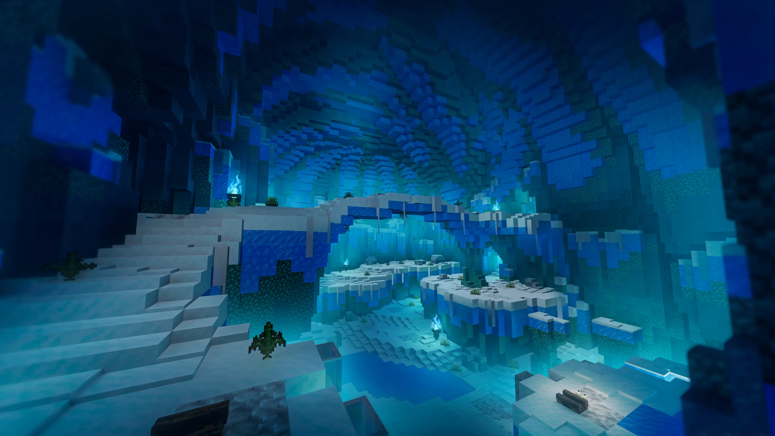 Minecraft cave scene with layered icy terraces and glowing blue water, viewed through a wide dark cavern opening. Pale ledges and bridges step across the center toward a bright turquoise pool.